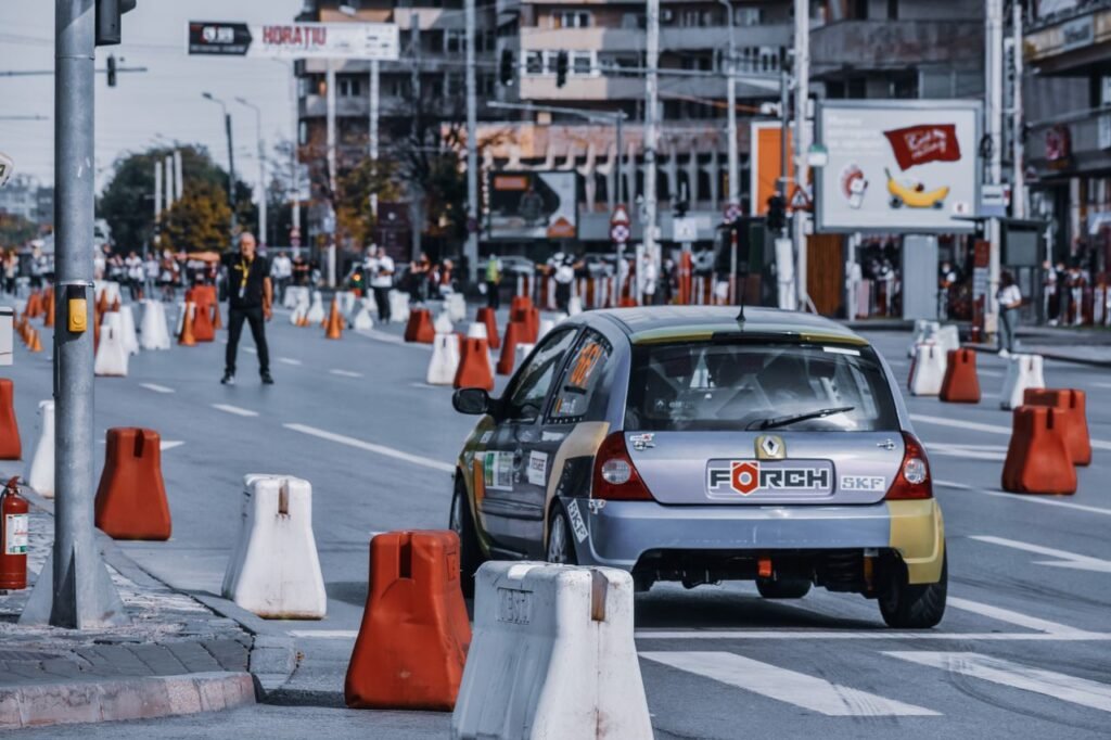 Modern automobile driving on asphalt road with barriers in street of contemporary town